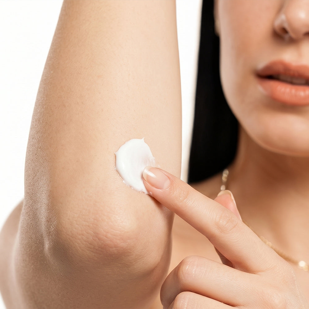 Young woman applying body cream on her arms