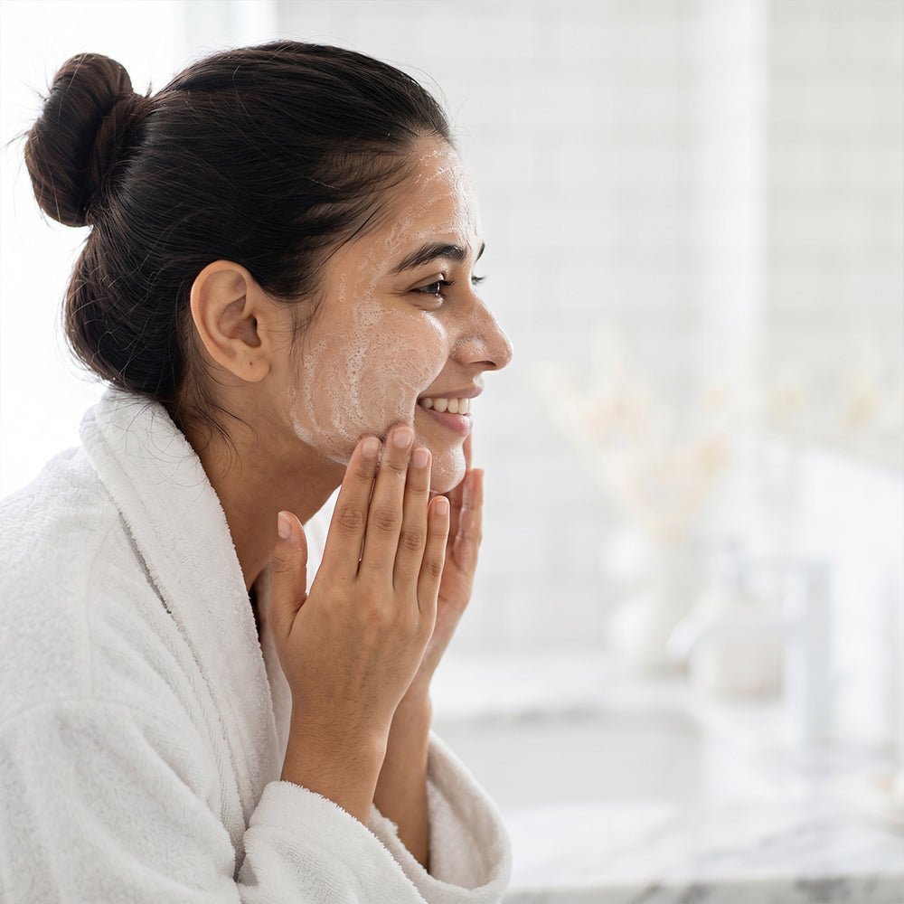 A beautiful woman applying a foaming face wash with a big smile on her face