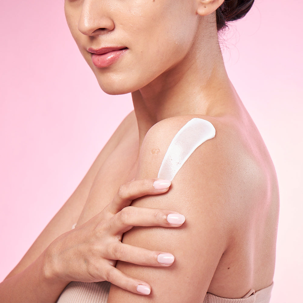 A beautiful woman applying body lotion on her arms