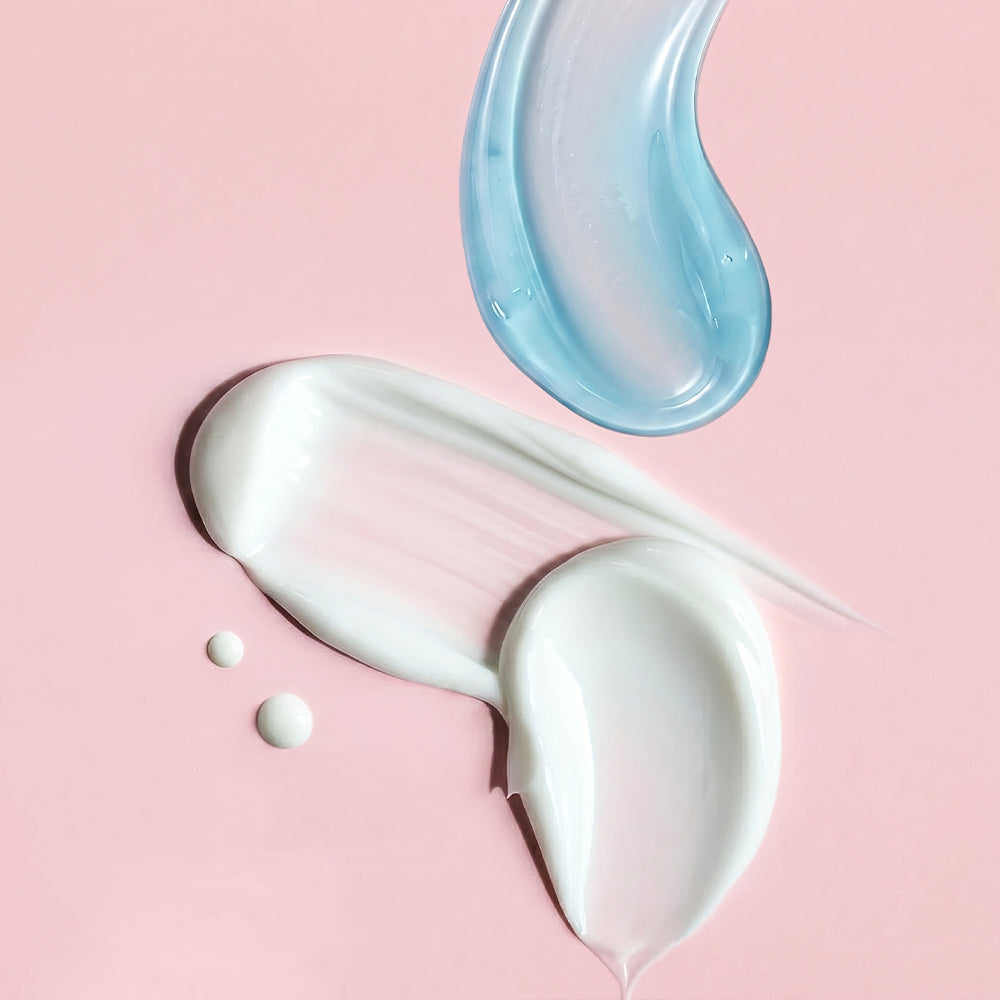 Differently textured skincare products smeared on a beige surface