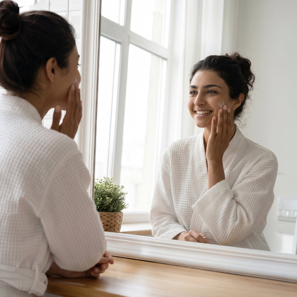 A young woman applying moisturiser on her face